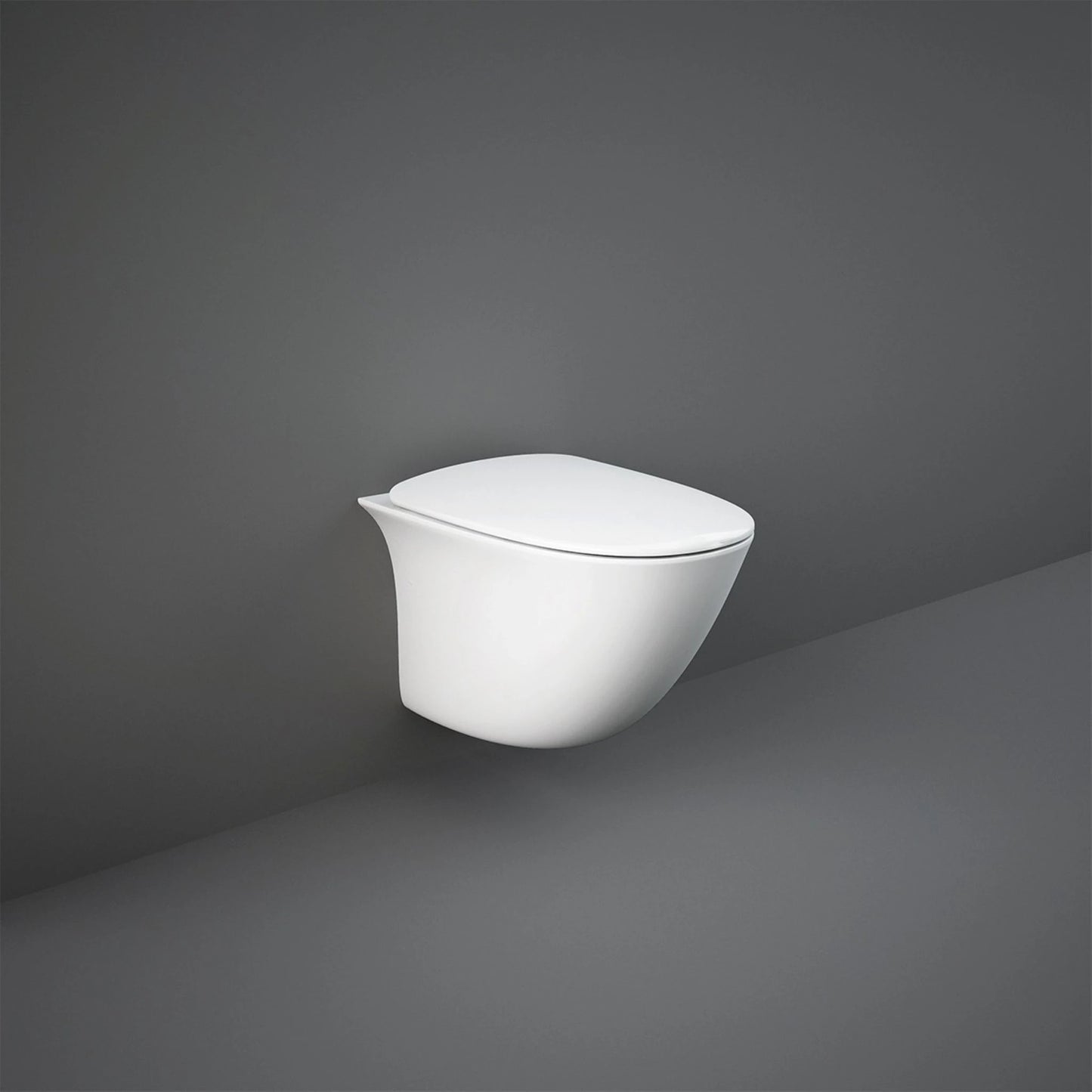 A grey space featuring a RAK Ceramics Sensation toilet equipped with the white normal-close seat cover, emphasizing a clean and hygienic atmosphere.