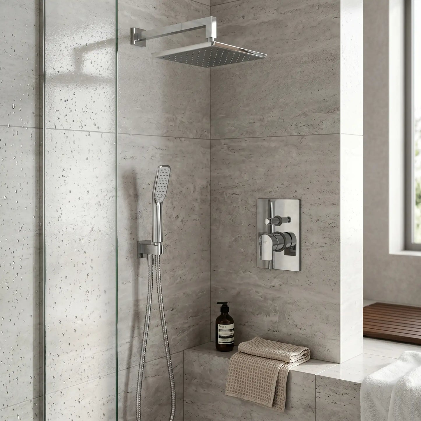 Modern luxury bathroom featuring the Strohm Teka Formentera concealed shower system installed on a grey stone-tiled wall, showcasing the overhead rain shower, handheld sprayer in use, and a floating wood vanity with a vessel sink.